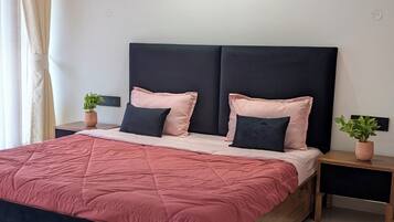 Un dormitorio moderno con una cama grande, dos mesitas de noche y tres obras de arte colgadas en la pared.