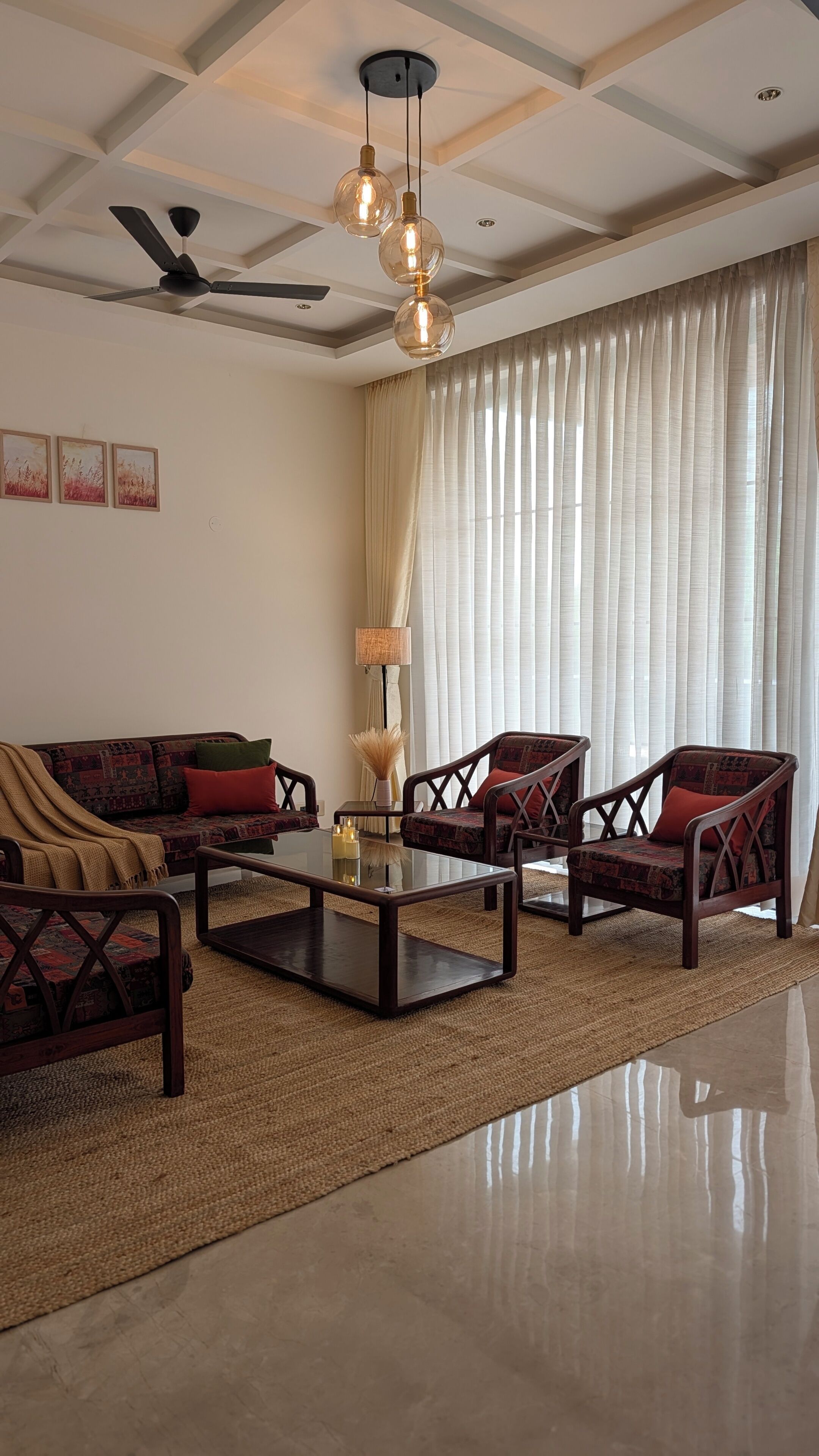 A living room with a sofa, two armchairs, a coffee table, a ceiling fan, and a large window with curtains.