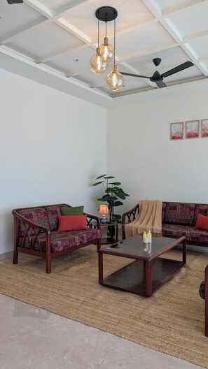 Un salon comprenant un ensemble de canapés, une table basse, un lampadaire et un ventilateur de plafond.