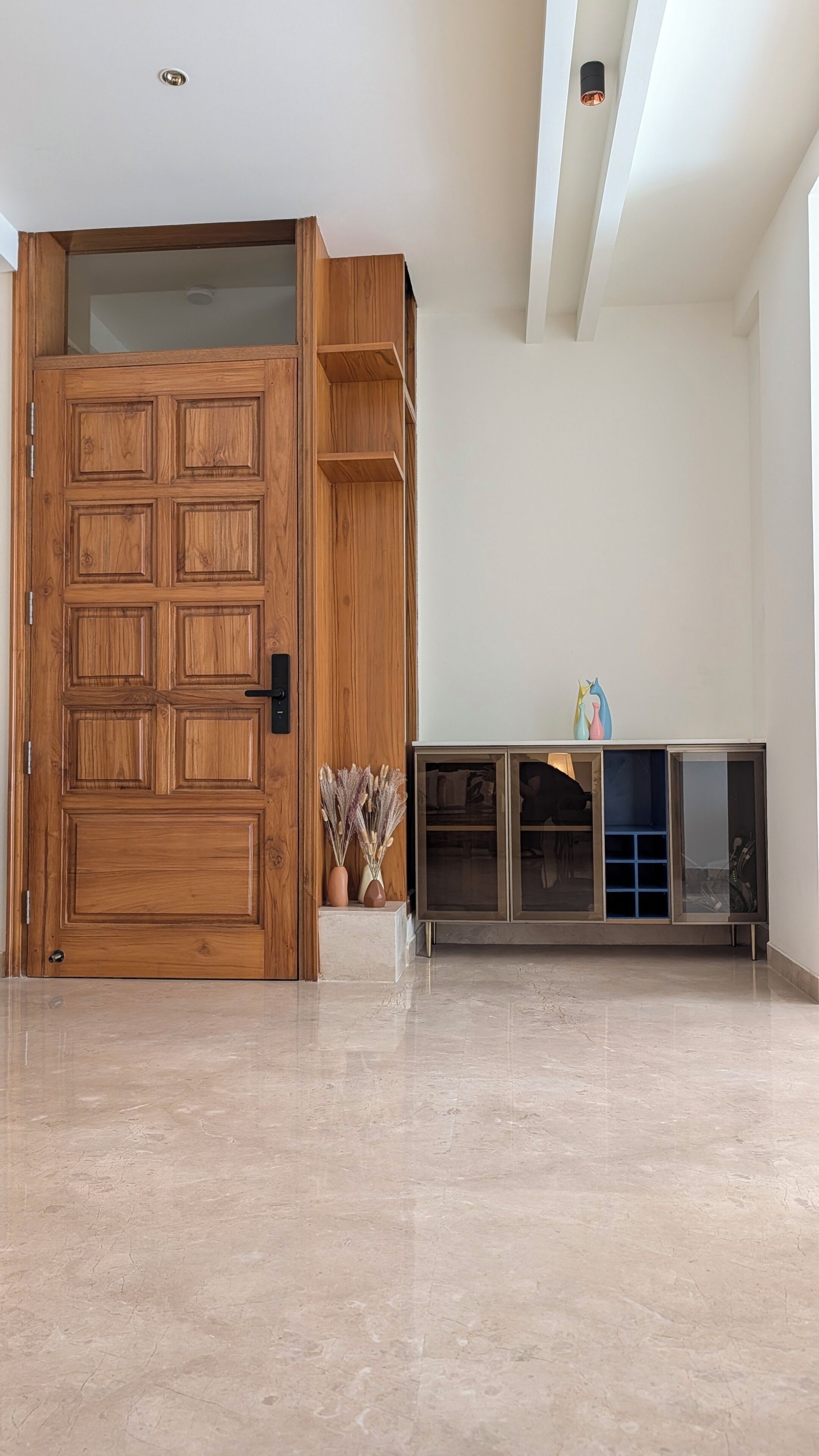A room with a wooden door, a cabinet with glass doors, and a tiled floor.