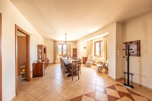 A spacious dining area with a long table, chairs, and a wooden cabinet.