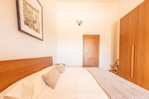 A bedroom with a wooden bed, a bedside table, a wardrobe, and a framed picture on the wall.
