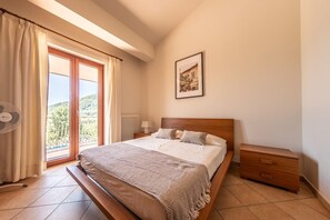 A bedroom with a bed, a nightstand, a radiator, a window with curtains, and a picture on the wall.