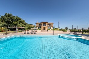 A two-story building with a swimming pool and lounge chairs.