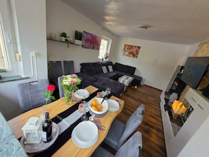 A modern living room with a sofa, dining table, and kitchen area. - Exclusive, bright apartment with balcony in the city, 1 Gbit Wifi, boxspringbeds (Kassel)