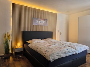 Un dormitorio con cama, mesita de noche y un cartel en la pared que dice 'HOME'.