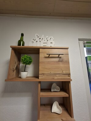 A wooden shelf with a potted plant, a decorative word, and a drawer.