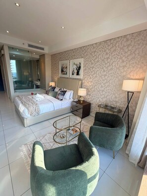 Een moderne slaapkamer met een bed, twee stoelen, een nachtkastje en een spiegel.