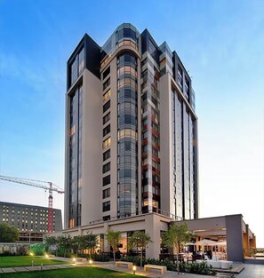 Een meerlaags hotel met een modern ontwerp, met een gebogen gevel en een combinatie van glas en massieve panelen.