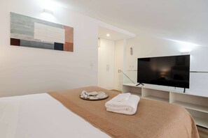 Una habitación de hotel con una cama, un televisor y una pequeña mesa con una bandeja.