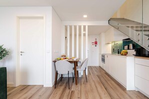 Una cocina moderna con comedor, piso de madera y una escalera.