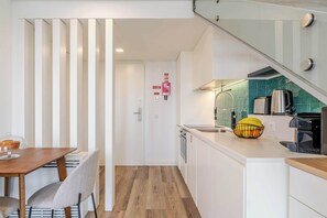 Cocina compacta con comedor, una escalera y una puerta con señalización de salida de emergencia.