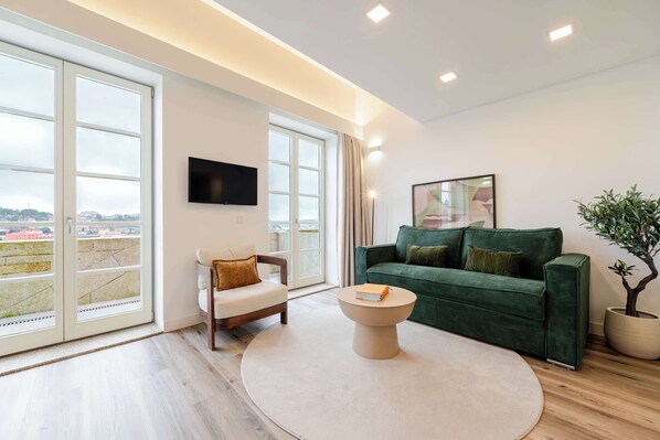 A modern living room with a sofa, a chair, a coffee table, and a TV mounted on the wall. - Stylish Flat Near the Douro River by HostWise (Vila Nova de Gaia)