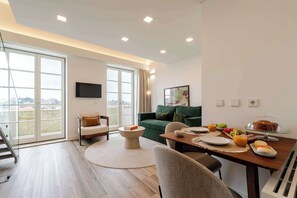 A modern living room with a dining area, large windows, a flat-screen TV, and a view of the cityscape. - Stylish Flat Near the Douro River by HostWise (Vila Nova de Gaia)