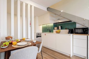 Una cocina moderna con comedor, que incluye una escalera, microondas y cafetera.