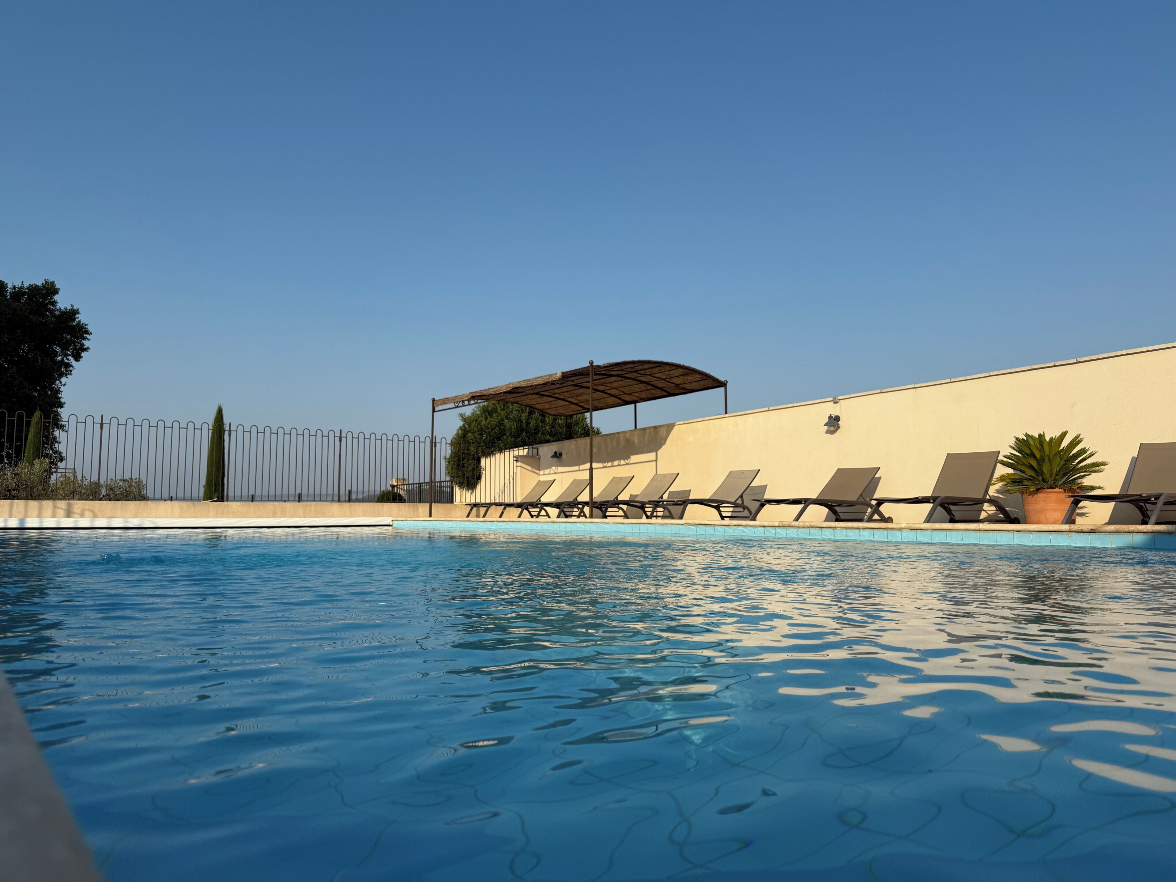 Una piscina con sillas de descanso y una zona sombreada.