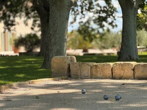 A paved area with a low stone wall and three spherical objects on the ground. - Le Tournesol - Laforest Estate Vacation Rental (Fontvieille)