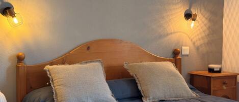 A neatly made bed with two pillows, a bedside table with a lamp, and a framed quote on the wall.