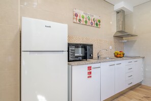 Eine moderne Küche mit einem weißen Kühlschrank, einer schwarzen Mikrowelle und einem Spülbecken.