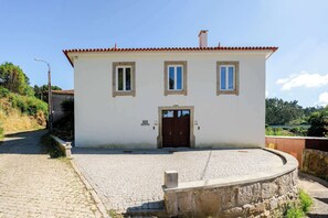 Ein zweistöckiges Gebäude mit weißer Fassade, einem roten Ziegeldach und einem zentralen Eingang mit einer Doppeltür.