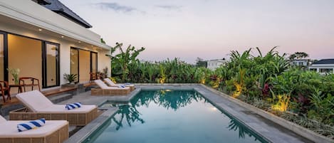 A modern pool area with lounge chairs and a well-maintained garden.