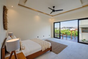 Una camera da letto con un letto, una ventola a soffitto, un'ampia finestra e vista sull'esterno.