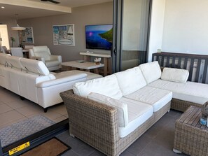 A modern living room with a white sofa set, a wicker accent piece, and a flat-screen TV on a stand. - 240m to BEACH,  OCEAN VIEWS,  Luxury Upmarket Large 2B 2B excellent location!! (Buddina)