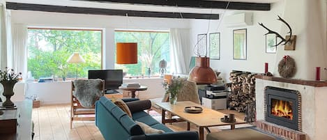A cozy living room with a fireplace, wooden flooring, a sofa, a table, and a television.