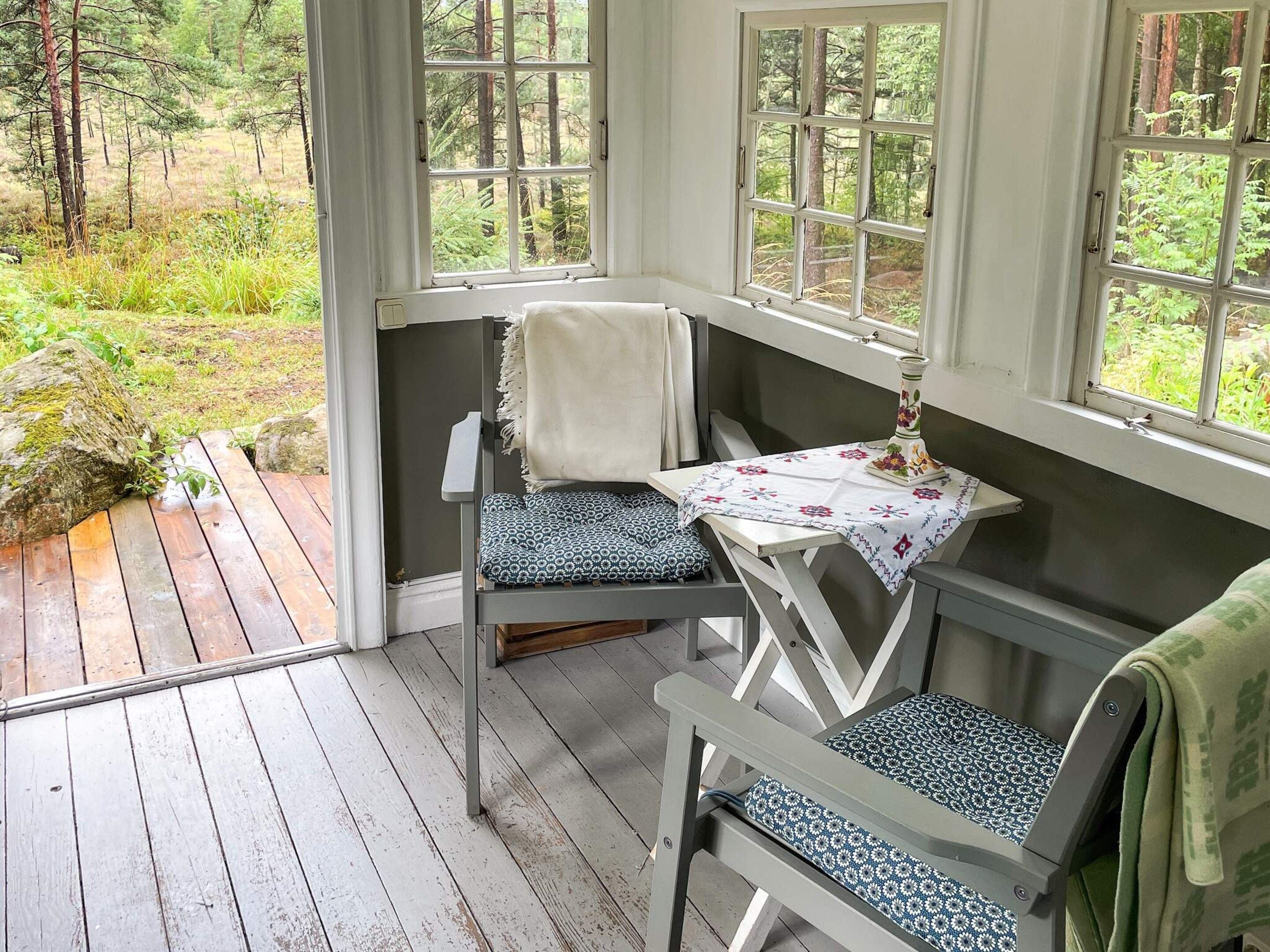 A wooden deck with a bench and a table, overlooking a forested area.