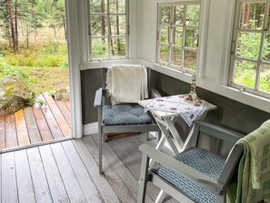 Terraza de madera con un banco y una mesa, con vista a un área boscosa.