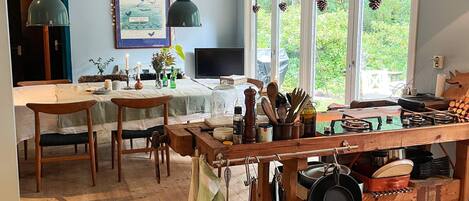 A kitchen with wooden cabinets, a dining table, and hanging pots.