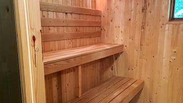 A wooden sauna with benches and a wall-mounted light fixture.