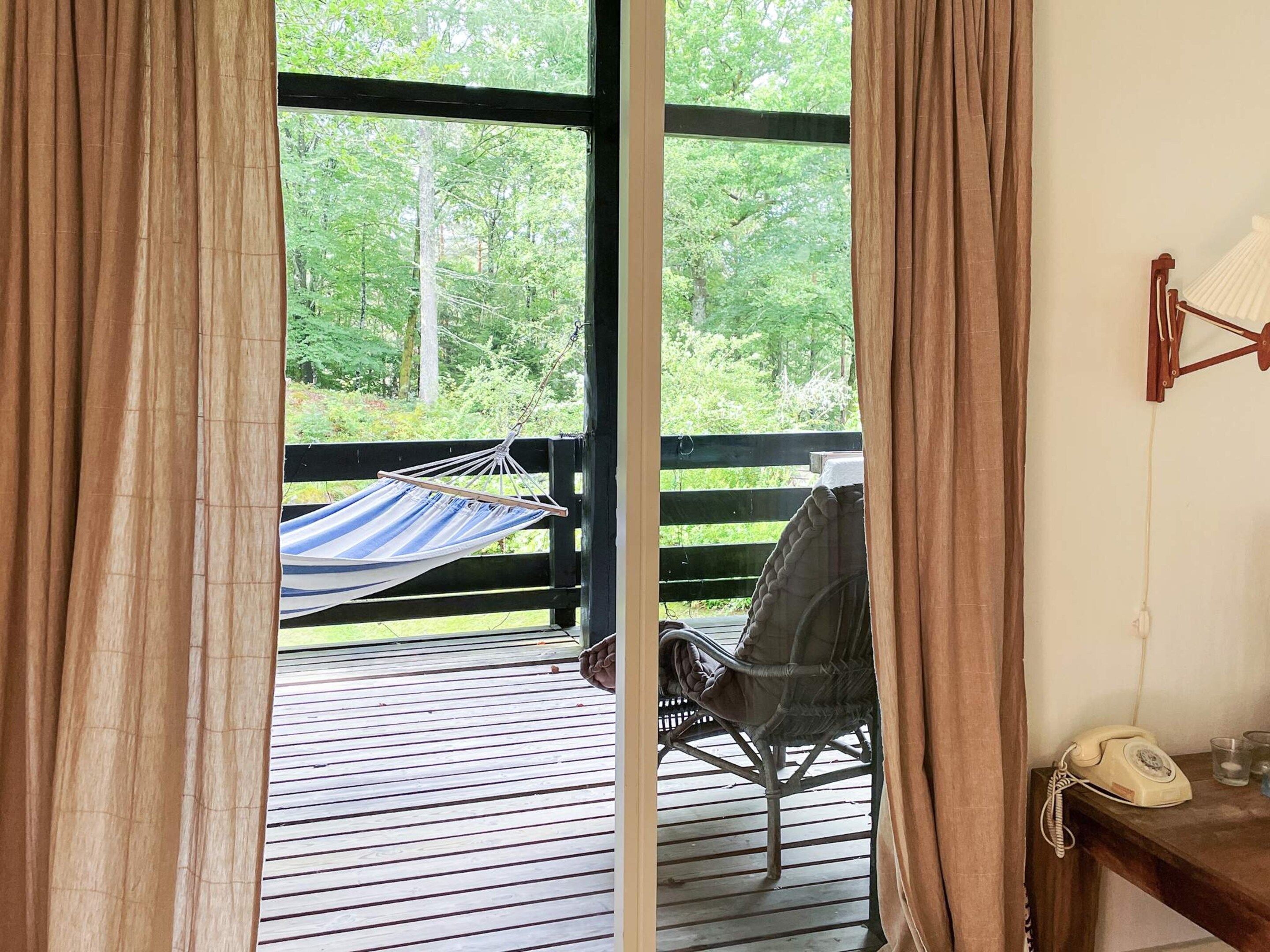 A wooden deck with a hammock, a chair, and a telephone.