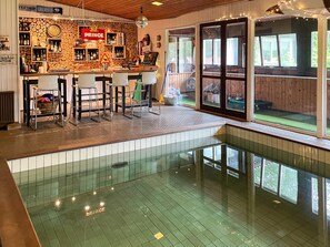 Uma área de bar com banquetas, piscina e vista para o exterior.