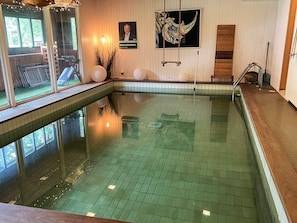 An indoor swimming pool with a tiled floor, a bench, and a wall-mounted picture. - 5 Star Holiday Home in Knared (Knared)