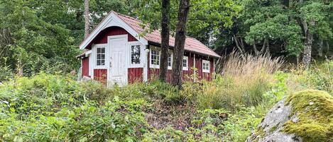 A red wooden cabin surrounded by dense forest.