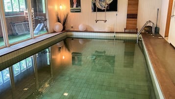 An indoor swimming pool with tiled walls and a clear water surface.