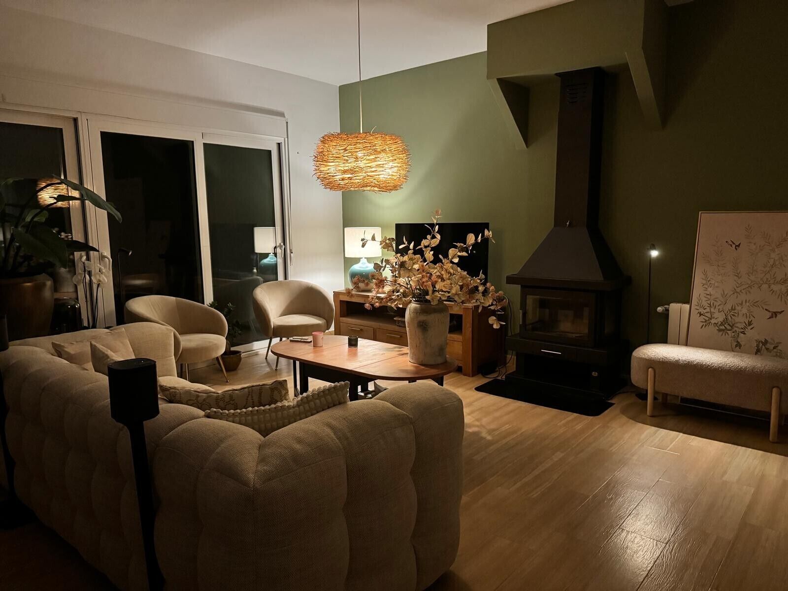 Een woonkamer met een bank, fauteuils, een salontafel, een open haard en een televisie.