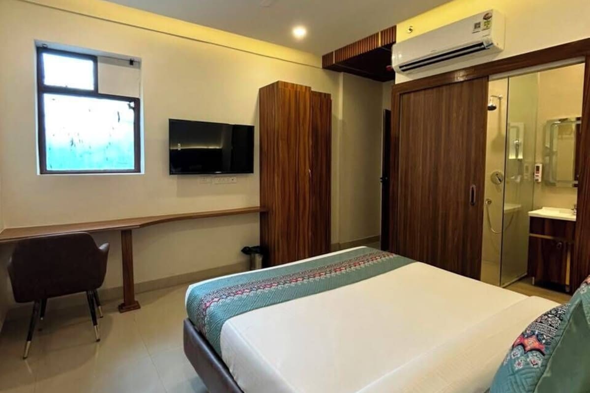 A bedroom with a bed, a desk, a TV, and a wardrobe.