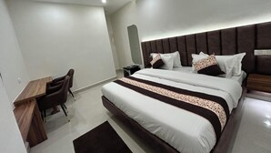 Quarto de hotel com uma cama grande, uma escrivaninha e uma cadeira.