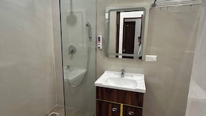 Uma casa de banho moderna com cabine de duche em vidro, toucador com espelho e sanita.