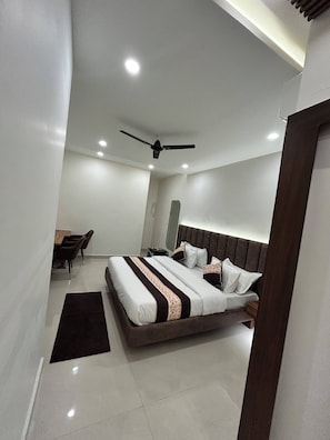 A modern bedroom with a bed, bedside table, and a ceiling fan. - Hotel Prime Elvista  (Zirakpur)