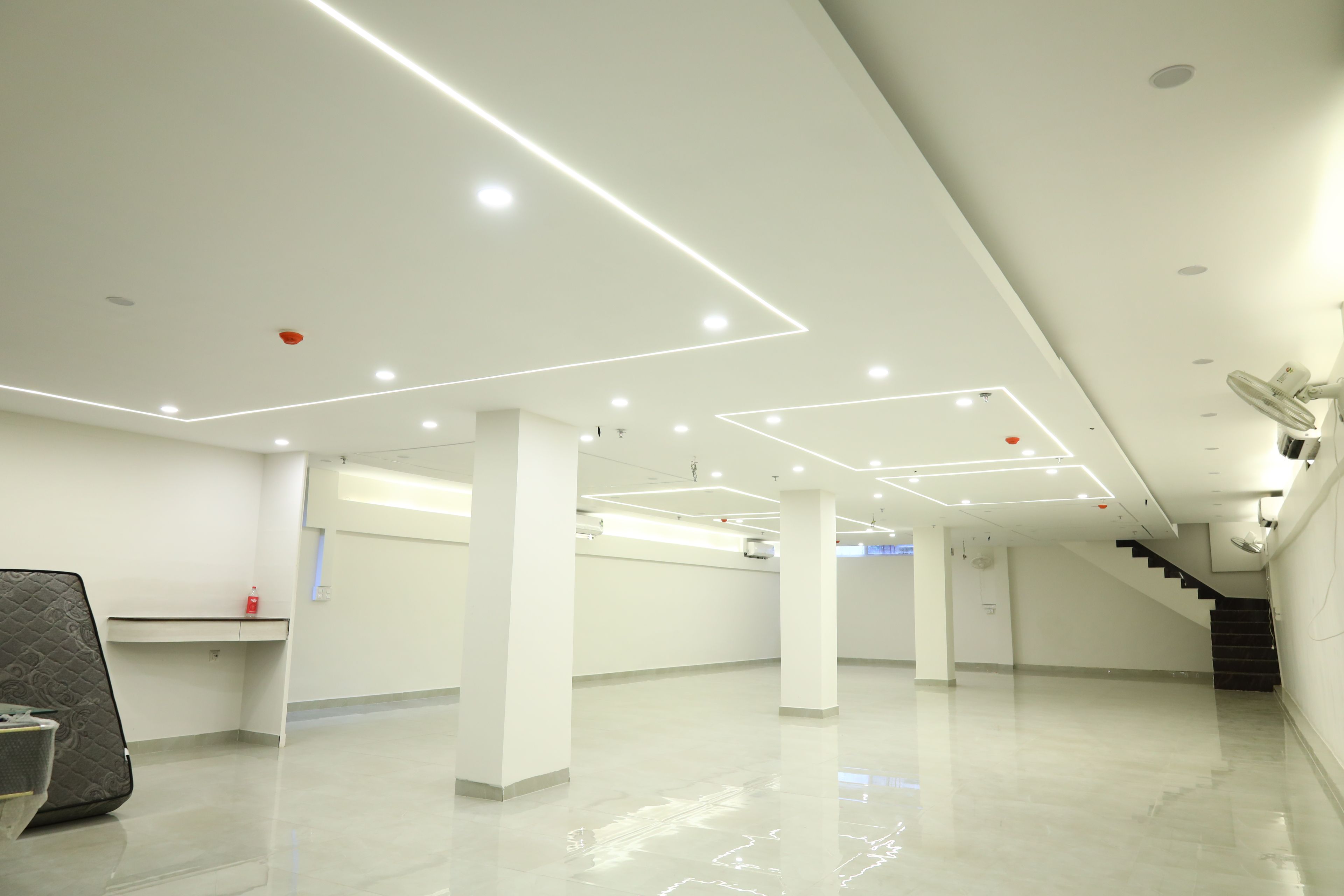 Un interior amplio y luminoso con diseño moderno, que cuenta con una columna central, una escalera y un mostrador de recepción.