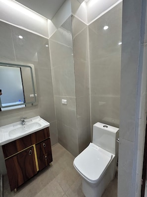 A bathroom with a white sink, mirror, and toilet. - Hotel Prime Elvista  (Zirakpur)