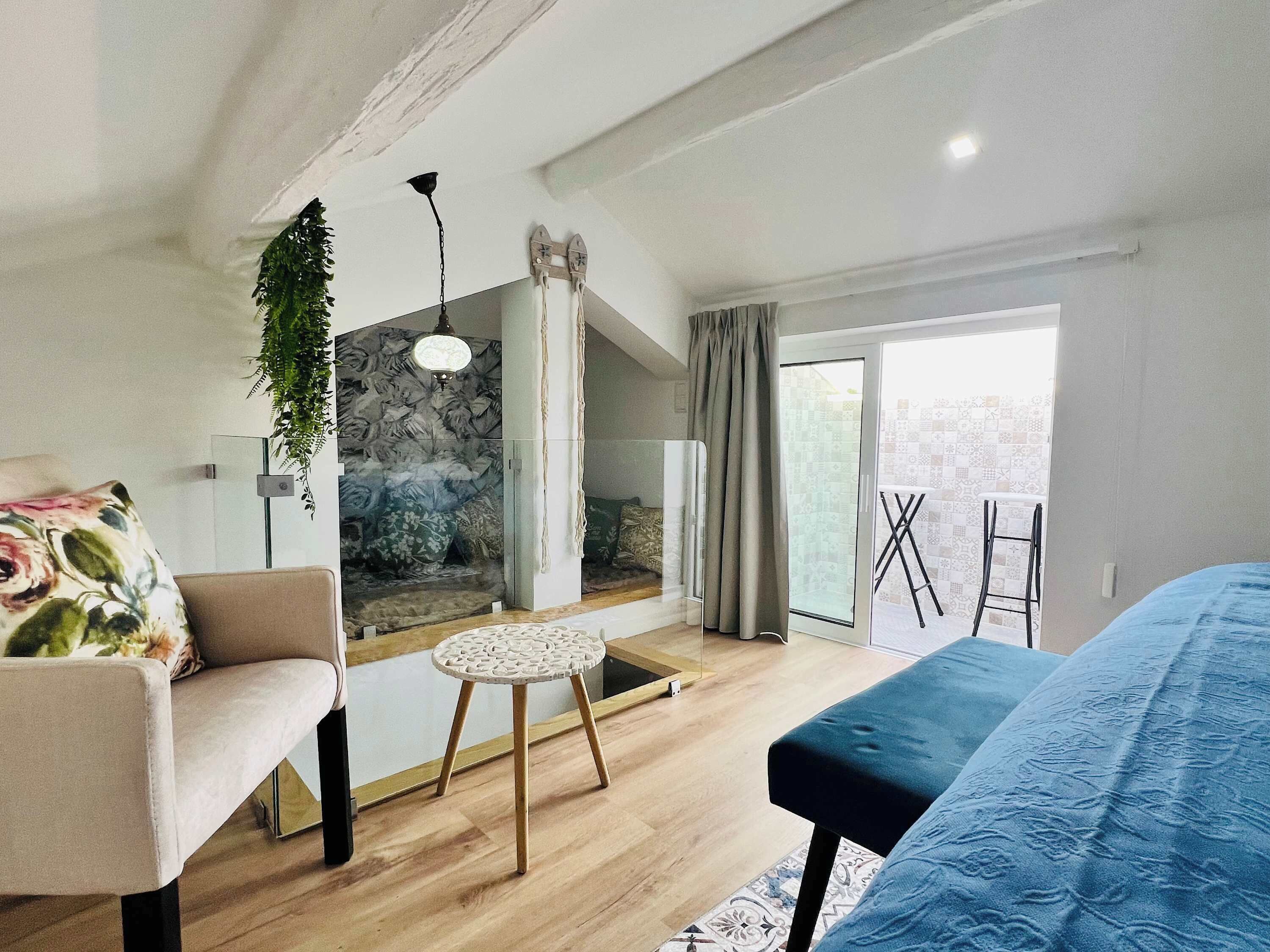 A modern living room with a sofa, a blue bench, a small round table, and a decorative wall.