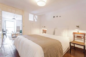 A bedroom with a large bed, a wooden chair, a nightstand, and a window. - Oak Valley Flats, Bairro Alto—2 minutes from Chiado (Lisboa)