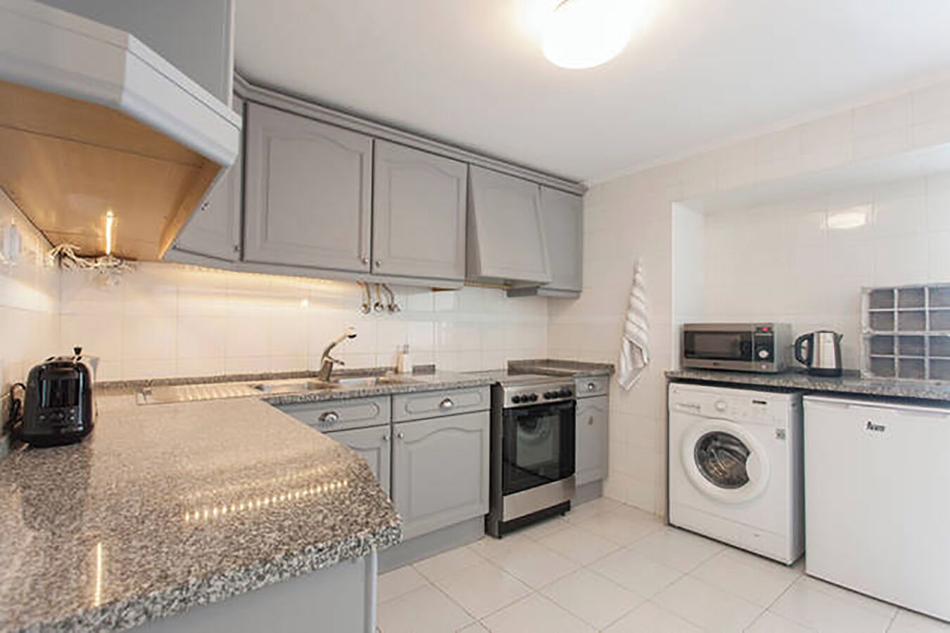 A modern kitchen with granite countertops, stainless steel appliances, and white cabinetry.