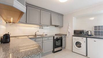A modern kitchen with granite countertops, stainless steel appliances, and white cabinetry.