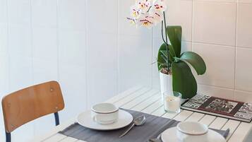 A dining table set with plates, bowls, and cutlery, a candle, and a potted orchid.
