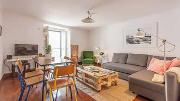 Un salon avec un canapé, une table basse et un téléviseur. Il y a également un coin repas avec des chaises et une table.